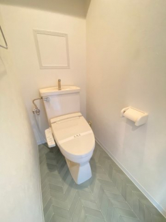 清潔感のある白いトイレです。緑のおしゃれな床がアクセントです。