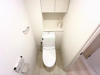 温水洗浄便座付きのトイレ。上部収納もあり、すっきりとした空間