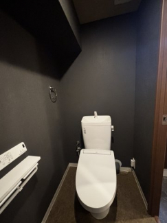 温水洗浄便座付きの清潔感あるトイレ。黒を基調としたクロスで生活感を感じさせないすっきりとした空間です。