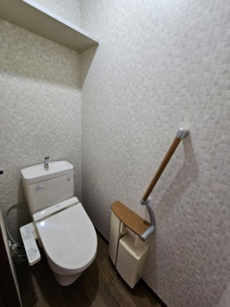 温水洗浄便座です。おしゃれな手すりとペーパーホルダー。棚もあるのでトイレットペーパーなどを置いておけますね