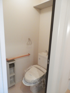 手すりも付いたトイレ。温水洗浄便座です。トイレットペーパーが置ける棚もあります