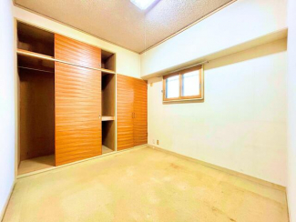壁一面に収納スペースが設けられた洋室で、衣類や季節物の収納に