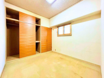 壁一面に収納スペースが設けられた洋室で、衣類や季節物の収納に